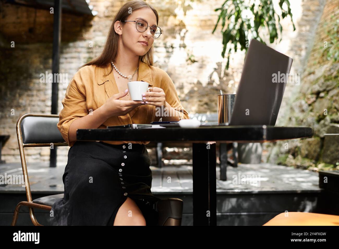 In einem warmen Café genießt eine junge Frau mit künstlichem Bein ihren Kaffee und verkörpert Widerstandsfähigkeit und Stil. Stockfoto