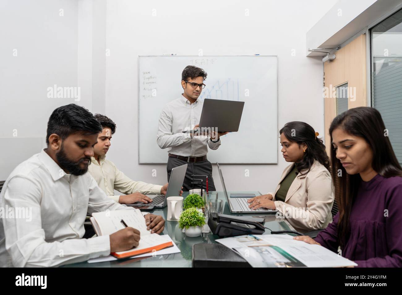 Ein Teamleiter, der an einem Online-Kundenmeeting in einem modernen Konferenzraum teilnimmt. Der Teamleiter ist fokussiert und engagiert in der Interaktion. Stockfoto