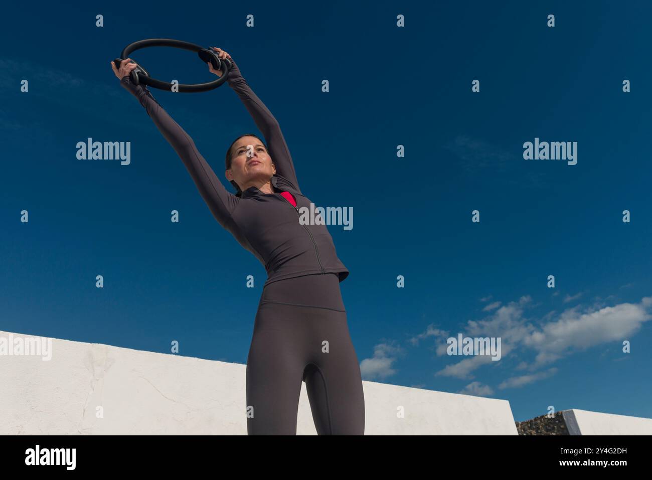 Sportliche Frau, die sich mit einem Pilates-Ring ausdehnt, Fitnesskonzept im Freien Stockfoto