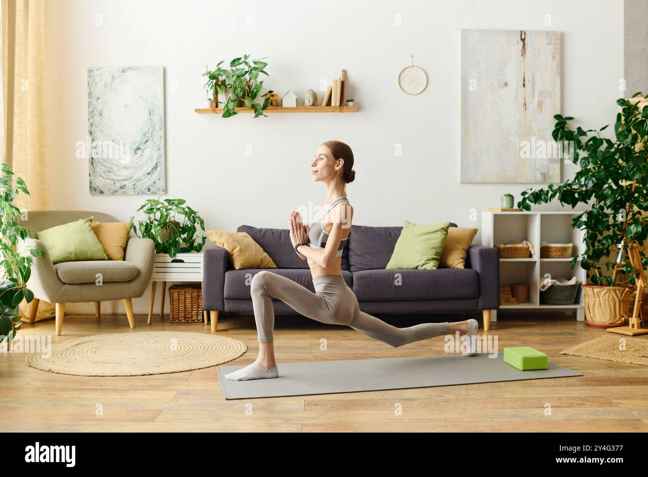 In einem ruhigen Wohnraum nimmt eine junge Frau mit Anorexie eine Yoga-Praxis auf, wobei sie sich auf ihr körperliches und geistiges Wohlbefinden konzentriert. Stockfoto