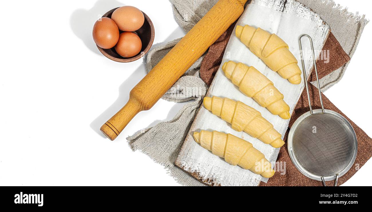 Gefrorene Croissants, der Prozess der Herstellung eines traditionellen Desserts. Komfortables Essen, klassisches Frühstück. Trendiges hartes Licht, dunkler Schatten, weißer Hintergrund, Verbot Stockfoto