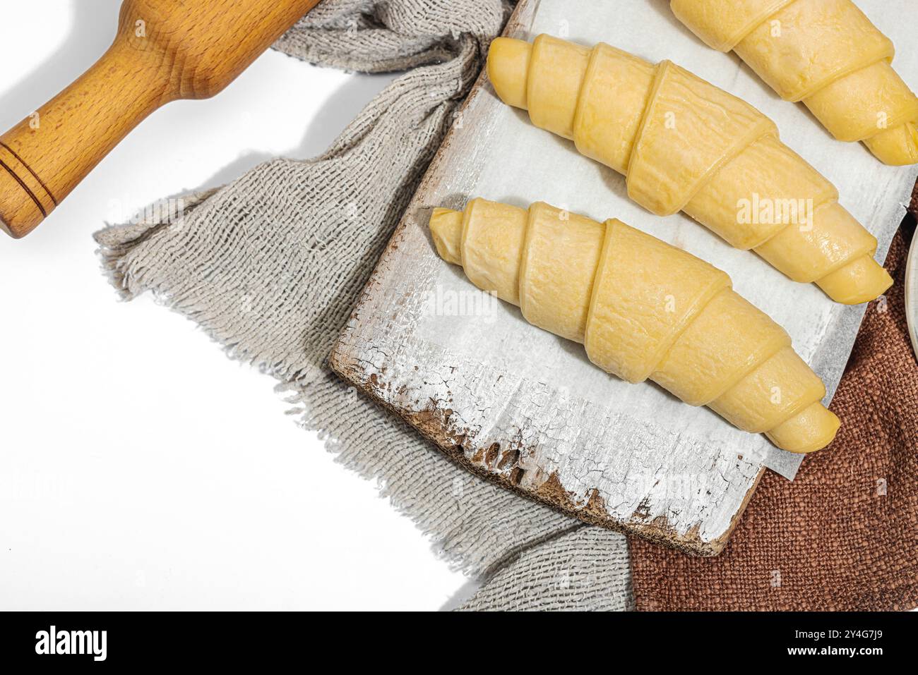 Gefrorene Croissants, der Prozess der Herstellung eines traditionellen Desserts. Komfortables Essen, klassisches Frühstück. Trendiges hartes Licht, dunkler Schatten, weißer Hintergrund, oben Stockfoto