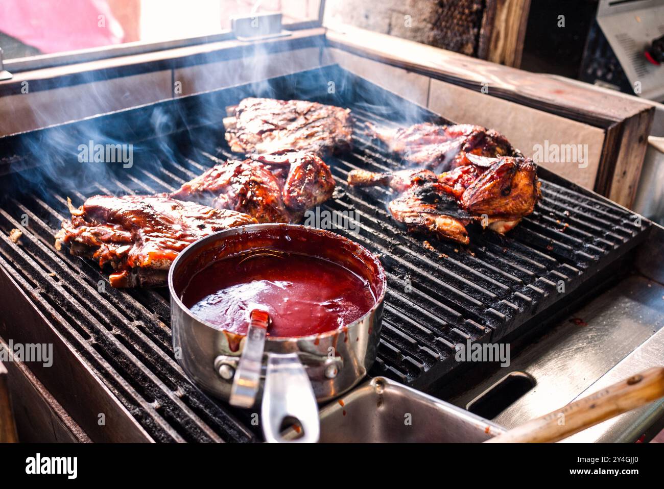 Barbecue Huhn und Rippchen im Uncle Joe's Barbecue Cruz Bay U.S. Virgin Islands // ST. JOHN, U.S. Virgin Islands – Barbecue Huhn und Rippchen brutzeln auf dem Grill im berühmten Onkel Joe's Barbecue in Cruz Bay. Uncle Joe's ist bekannt für seine köstlichen Grillspezialitäten im Inselstil und ist ein beliebter Ort für Einheimische und Besucher. Hier werden köstliche karibische Gerichte in entspannter Atmosphäre im Freien serviert. Stockfoto