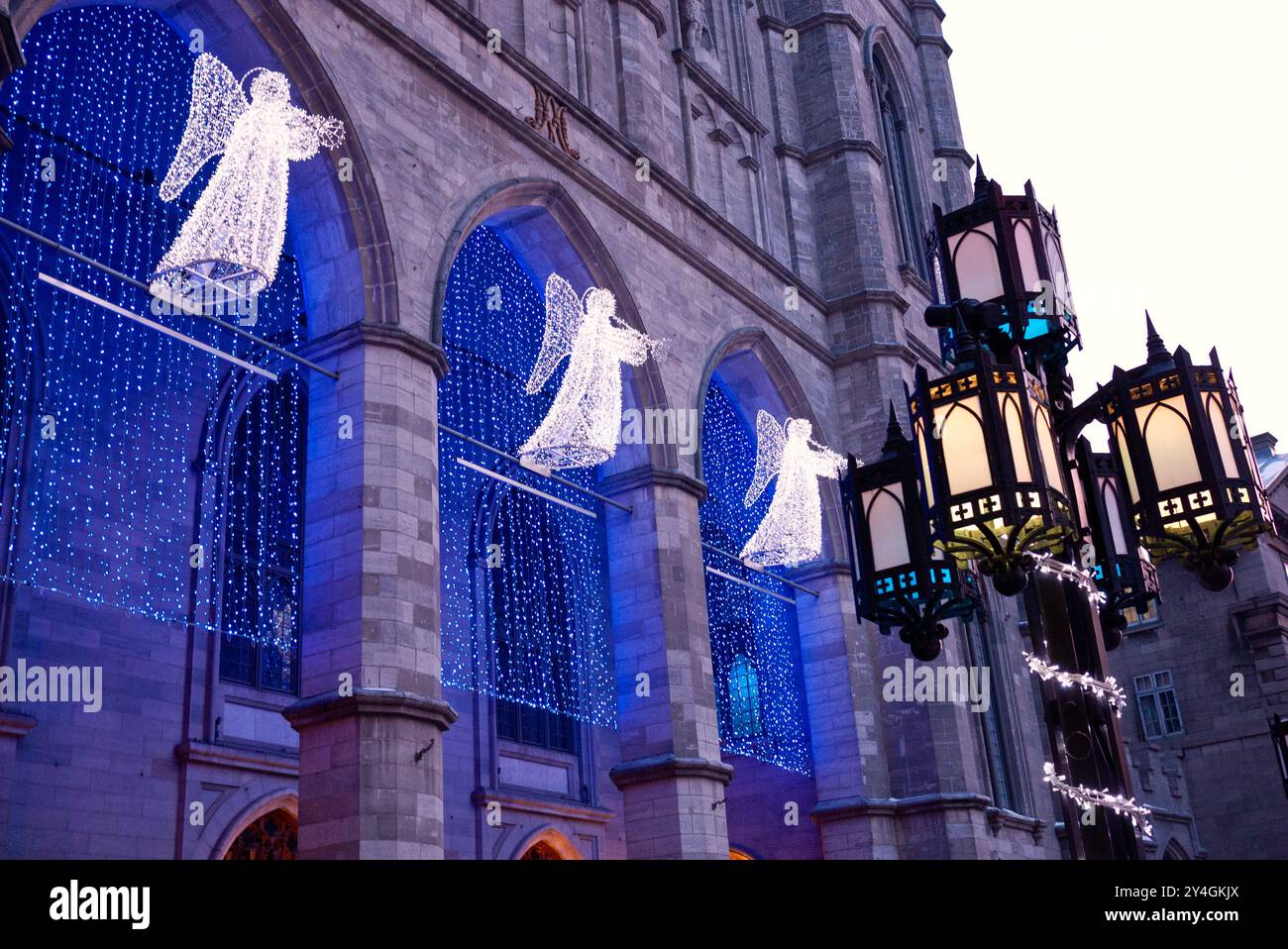 MONTREAL, Kanada – die Engelsleuchten beleuchten den Eingang der Basilika Notre-Dame in der Weihnachtszeit im Revival der Gotik. Die historische katholische Kirche, die 1829 fertiggestellt wurde, steht als Herzstück der Feierlichkeiten in Montreal im Stadtteil Old Montreal. Die dramatische Beleuchtung unterstreicht die architektonischen Details der Basilika und schafft eine festliche Atmosphäre für Winterbesucher. Stockfoto