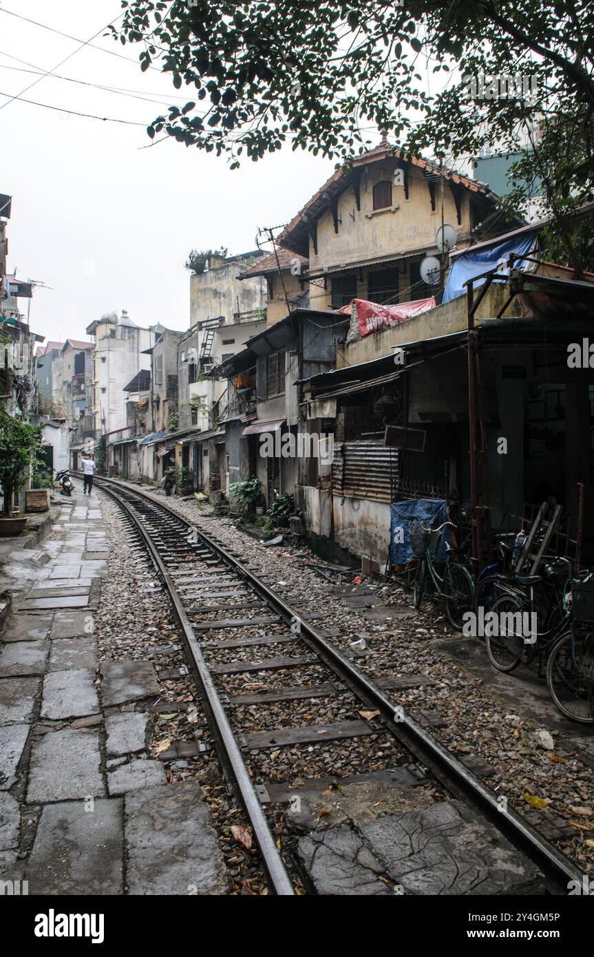 Train Street Hanoi Vietnam // HANOI, Vietnam — die Gleise führen durch ein altes Viertel in Hanoi, wobei die Gleise sehr nahe an die umliegenden Gebäude liegen. Die berühmte Bahnstraße ist ein bekannter Teil der Stadt, wo der Zug nur wenige Zentimeter von Häusern und Geschäften in der engen Gasse entfernt vorbeifährt. Stockfoto