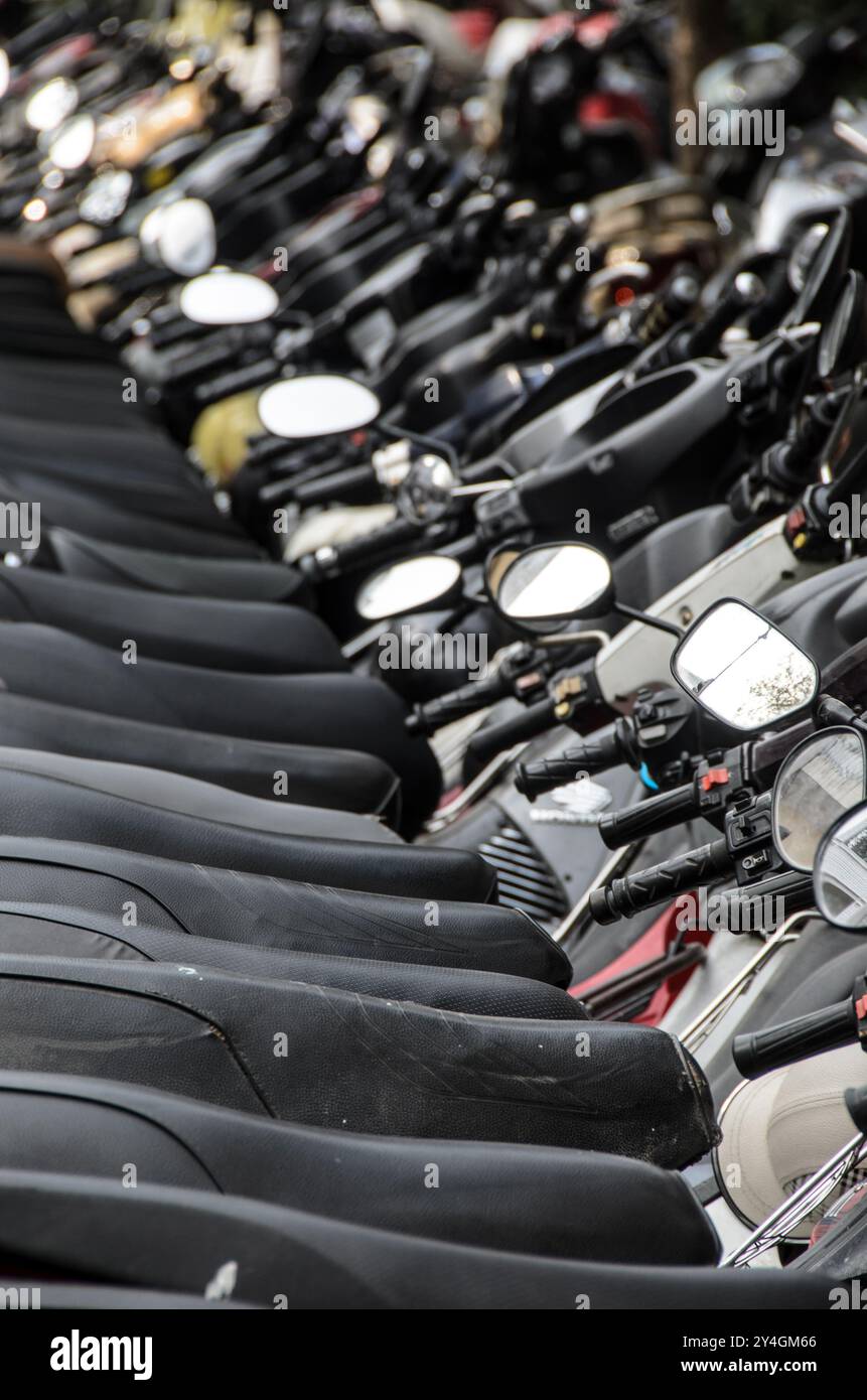 HANOI Vietnam // HANOI, Vietnam — Eine lange Reihe von Motorrädern und Motorrollern befindet sich am Rande einer Straße in der Altstadt von Hanoi. Die Szene spiegelt die Abhängigkeit der Stadt von Zweirädern für den Transport wider, ein häufiger Anblick in diesem geschäftigen Teil Vietnams. Stockfoto
