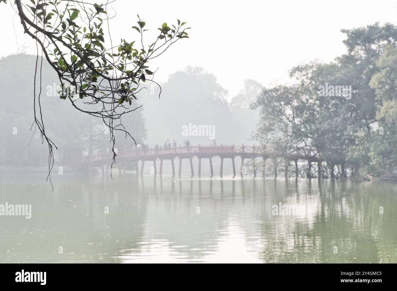 Die Huc Bridge Hoan Kiem Lake Hanoi Vietnam // HANOI, Vietnam — die Huc Bridge, auch bekannt als Morning Sunlight Bridge, verbindet das Ufer des Hoan Kiem Lake mit der Jade Island im Zentrum von Hanoi. Die kupferfarbene Holzbrücke führt zum Ngoc Son Temple, einem historischen buddhistischen Tempel aus dem 18. Jahrhundert. Die reich verzierte Struktur dient sowohl als funktionale Kreuzung als auch als symbolisches Tor zur heiligen Stätte. Stockfoto