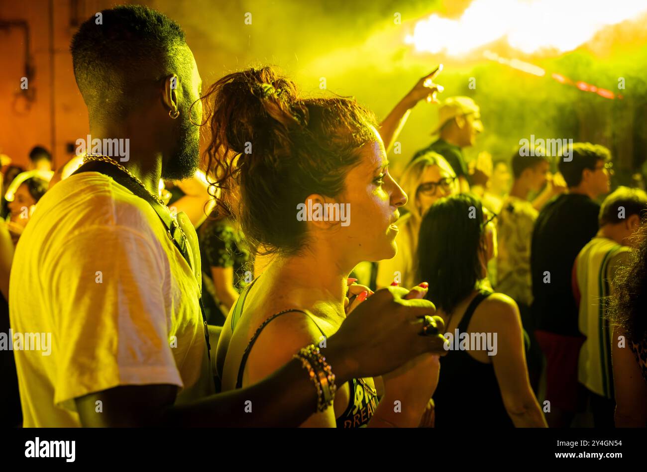 Ein junges gemischtes ethnisches Paar in einer Menge italienischer Leute, das ein kostenloses Nachtkonzert auf dem Platz in Depressa, einem Dorf in Apulien, freudet. Stockfoto