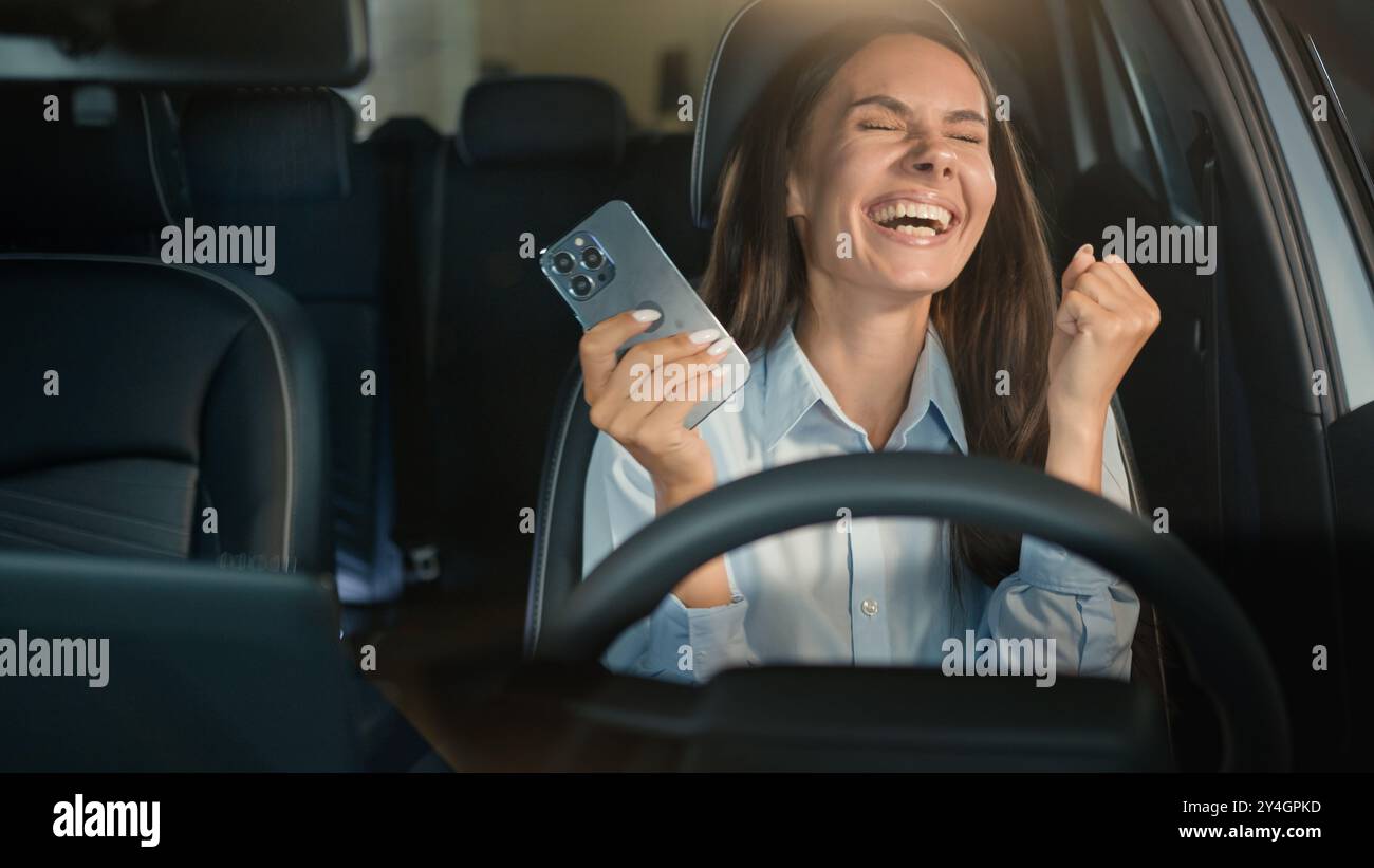 Kaukasische Geschäftsfrau glücklich aufgeregtes Mädchen Geschäftsfrau erfolgreiche Gewinnerin weibliche Fahrerin im Auto Auto Auto gewinnen Handy Erfolg Erfolg Erfolg Erfolg Erfolg Stockfoto
