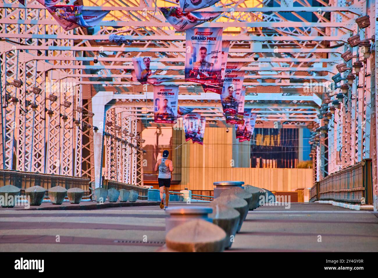 Jogger auf der Nashville Bridge bei Sonnenaufgang mit Blick auf die Grand Prix Banners auf Augenhöhe Stockfoto