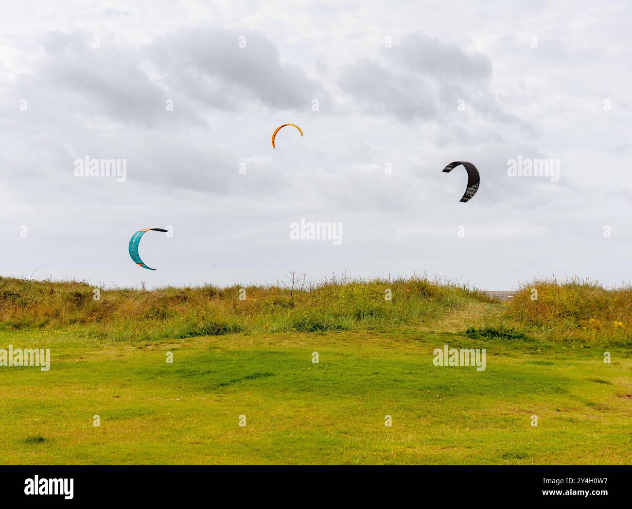 Drei Kitesurfen und Kiteboarden am Nordstrand des Barassie Beach in der Nähe von Troon in Schottland während eines windigen Sommers im Jahr 2024 Stockfoto