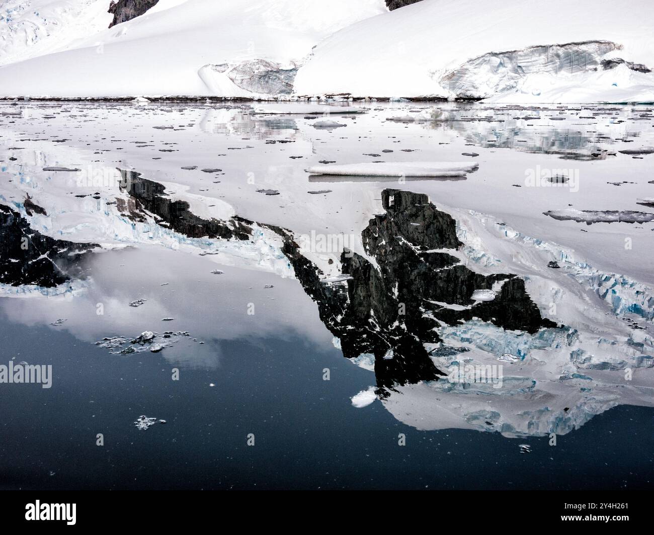 Cuverville Island Mountains and Reflections Antarktis // CUVERVILLE ISLAND, Antarktis – glasklare Gewässer spiegeln perfekt die schroffen, schneebedeckten Berge von Cuverville Island auf der westlichen Seite der Antarktischen Halbinsel wider. Die Insel liegt im Errera-Kanal zwischen der Insel Rongé und der Halbinsel Arctowski und ist für ihre dramatische Küste und unberührte Wildnis bekannt. Cuverville Island ist ein beliebtes Ziel für Antarktisexpeditionen und bietet Besuchern einen Einblick in die spektakuläre Landschaft des Kontinents und die vielfältige Tierwelt, darunter eine der größten Pinguinkolonien der Re Stockfoto