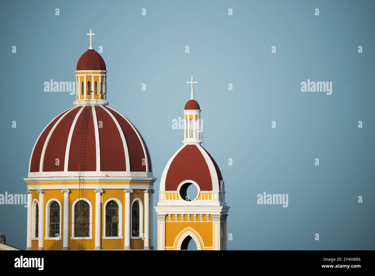 Kathedrale von Granada Dom und Glockenturm Granada Nicaragua // GRANADA, Nicaragua - die Kathedrale von Granada verfügt über eine charakteristische Kuppel und einen Glockenturm, die die Skyline der Stadt dominieren. Die Kathedrale, offiziell als Kathedrale von Granada oder Catedral de Granada bekannt, ist eine der wichtigsten religiösen Kolonialstrukturen Nicaraguas. Ursprünglich 1583 erbaut, stammt das heutige Gebäude hauptsächlich aus dem frühen 18. Jahrhundert, nachdem frühere Bauten durch Piratenangriffe beschädigt wurden. Die neoklassizistische Fassade und barocke Elemente der Kathedrale spiegeln die üblichen architektonischen Einflüsse wider Stockfoto