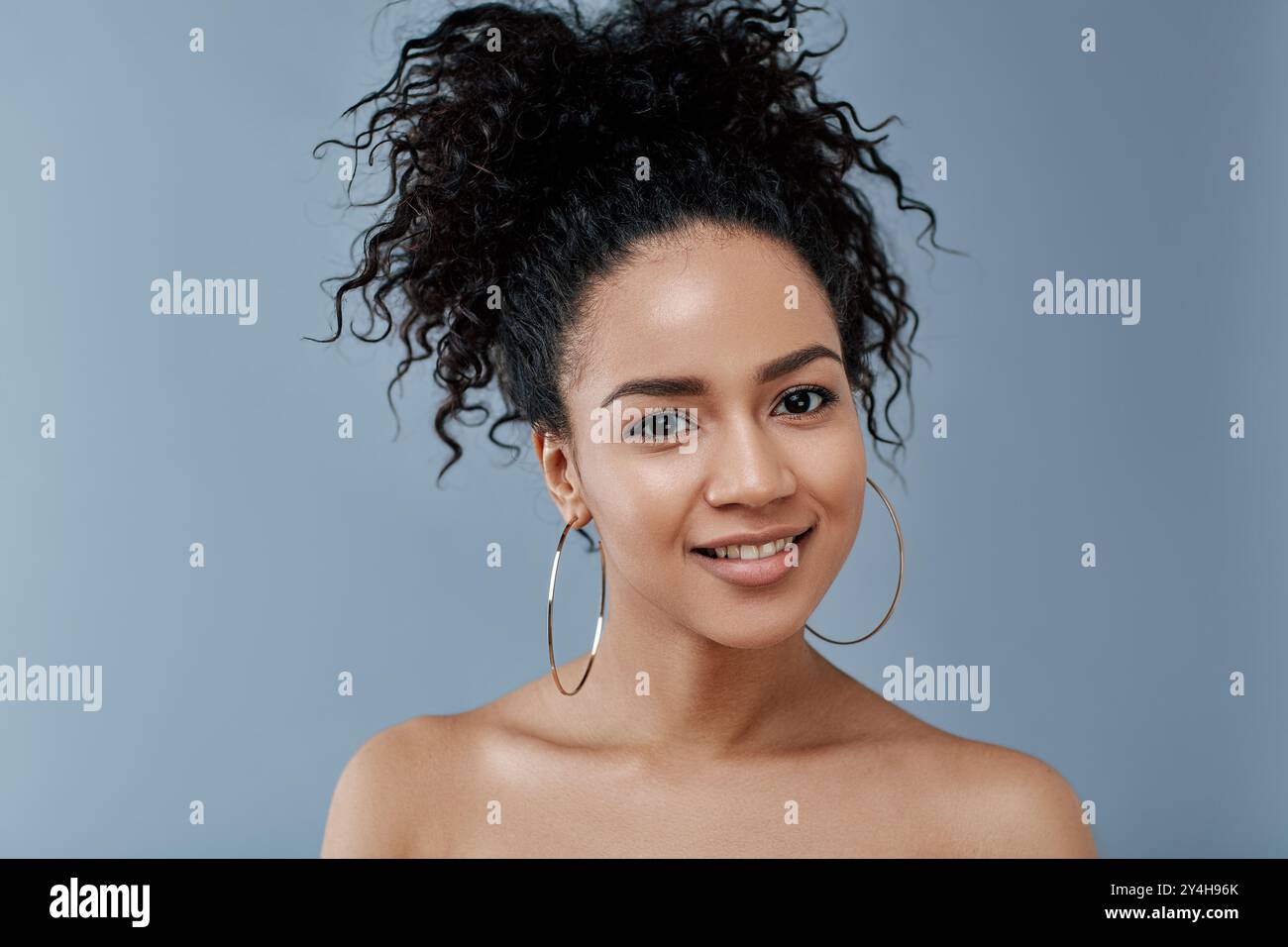 Junge Frau mit natürlicher Schönheit, die auf grauen Hintergrund in die Kamera schaut Stockfoto