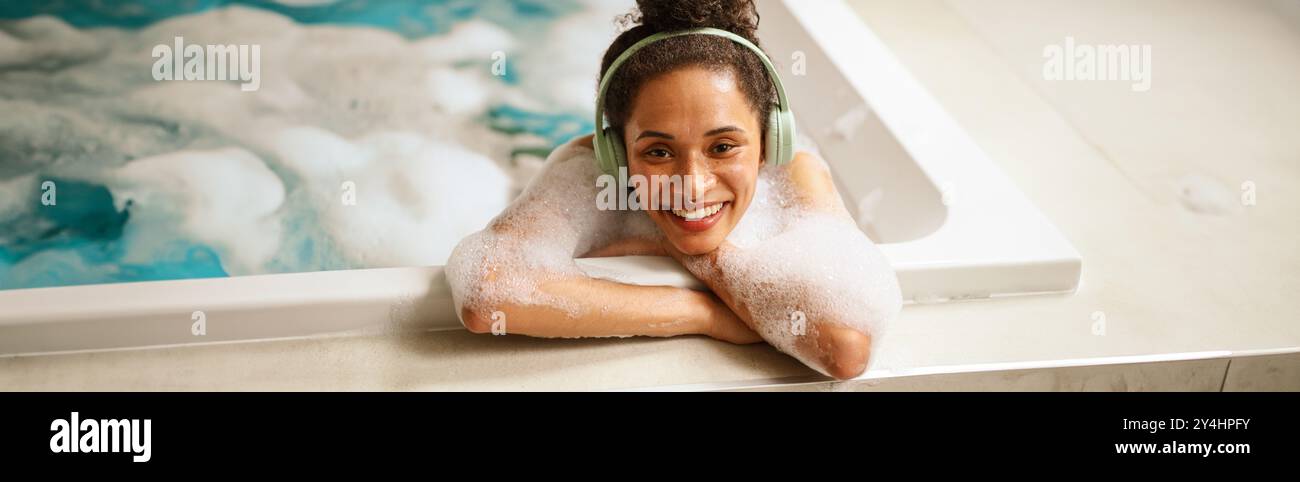 Eine Frau mit Kopfhörern nimmt ein Bad in einem Whirlpool Stockfoto