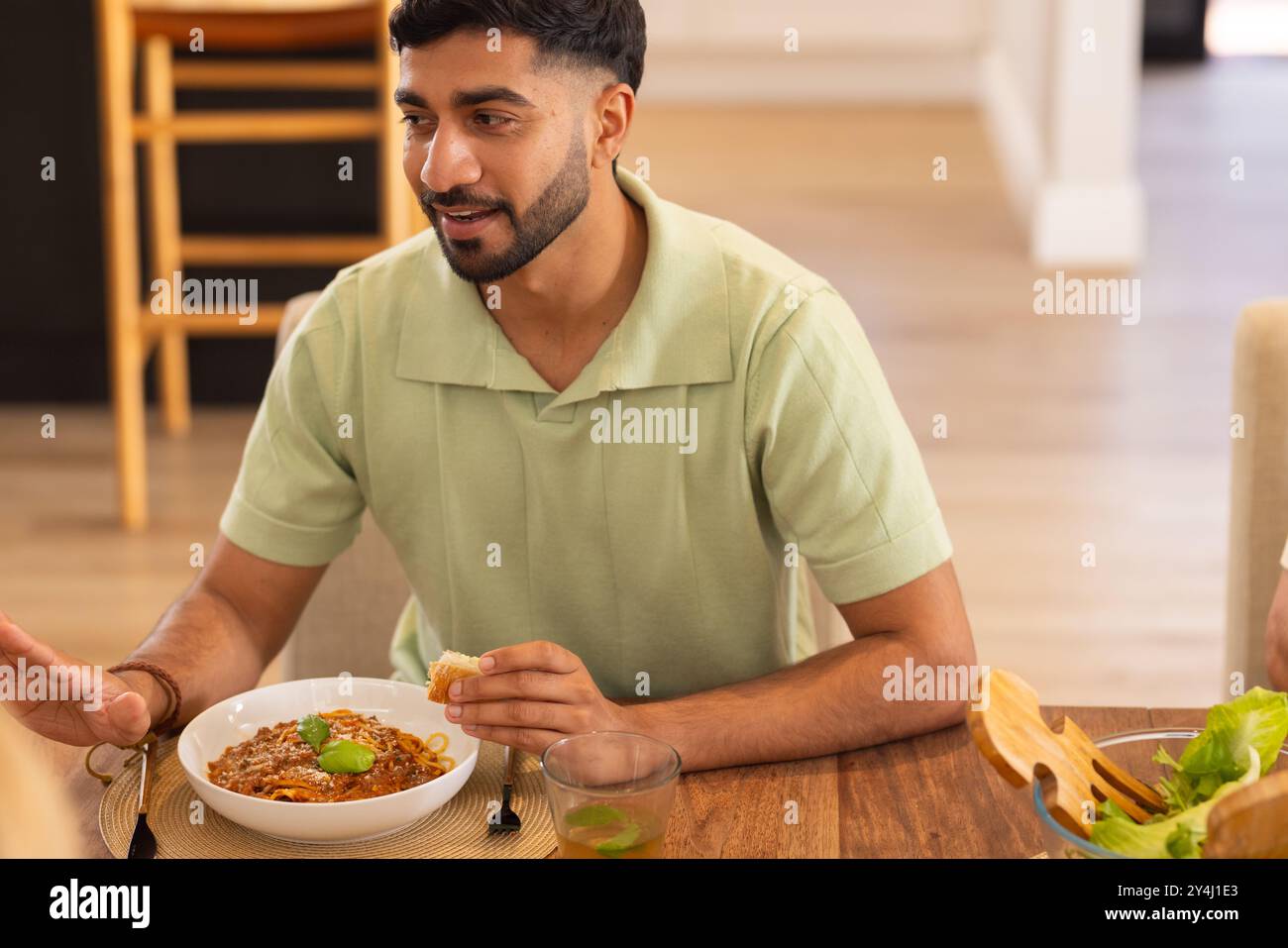 Pasta essen und reden, Mann genießt Essen mit verschiedenen Freunden am Esstisch Stockfoto