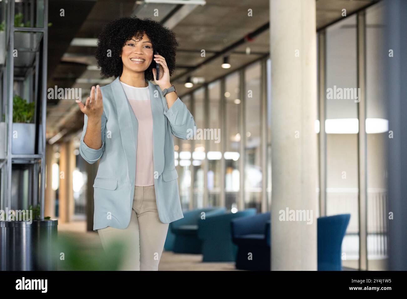 Gehen Sie im Büro, Geschäftsfrau spricht mit Smartphone und lächelt selbstbewusst, Kopierraum Stockfoto