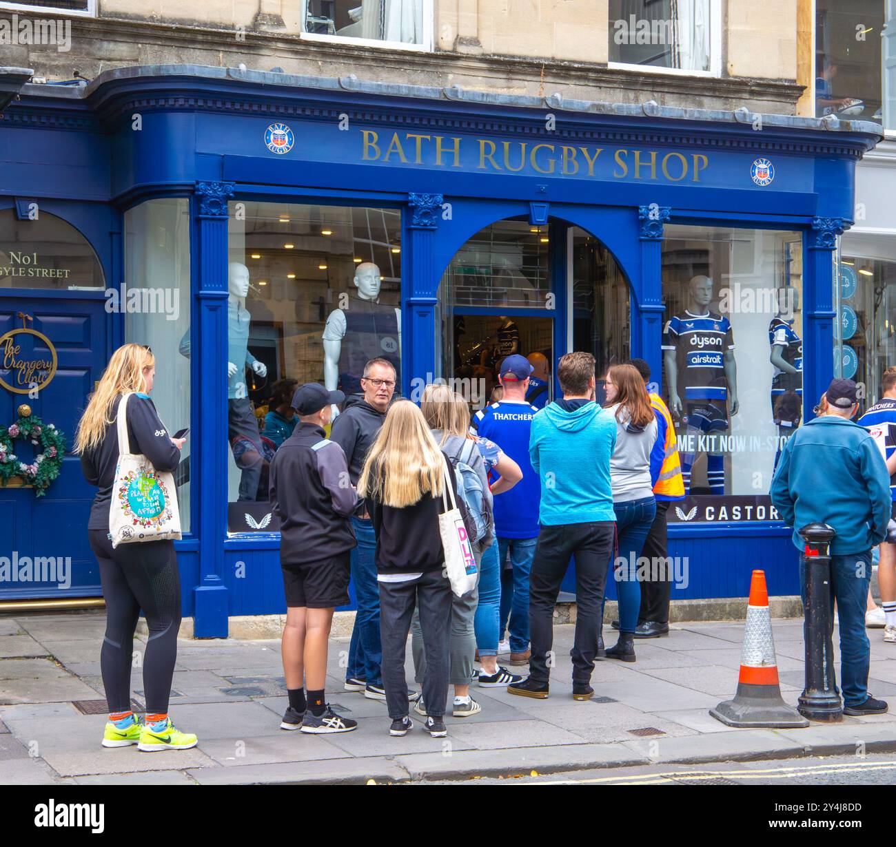 Gruppe von Leuten, die vor dem bunten Bath Rugby Shop anstehen. Stockfoto