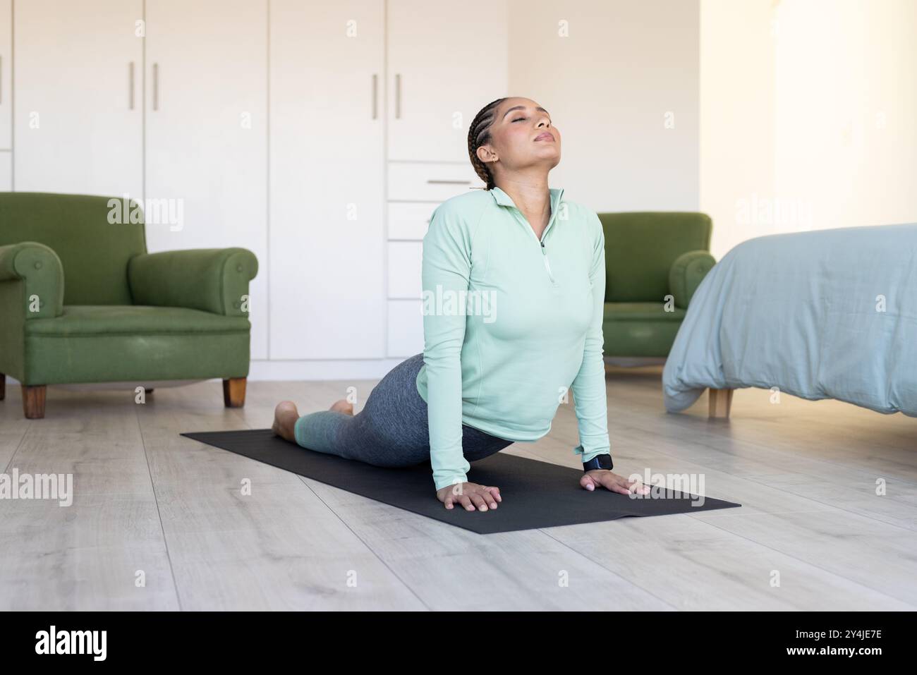 Yoga üben, Frau in bequemem Zuhause auf Yogamatte Stockfoto