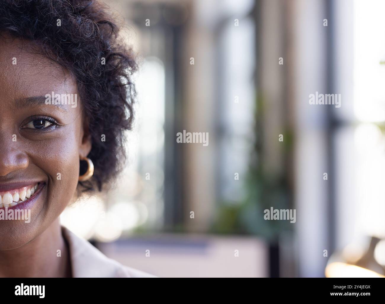 Lächelnde Frau im Büro, die Ohrringe trägt, positives Arbeitsumfeld zeigt Stockfoto