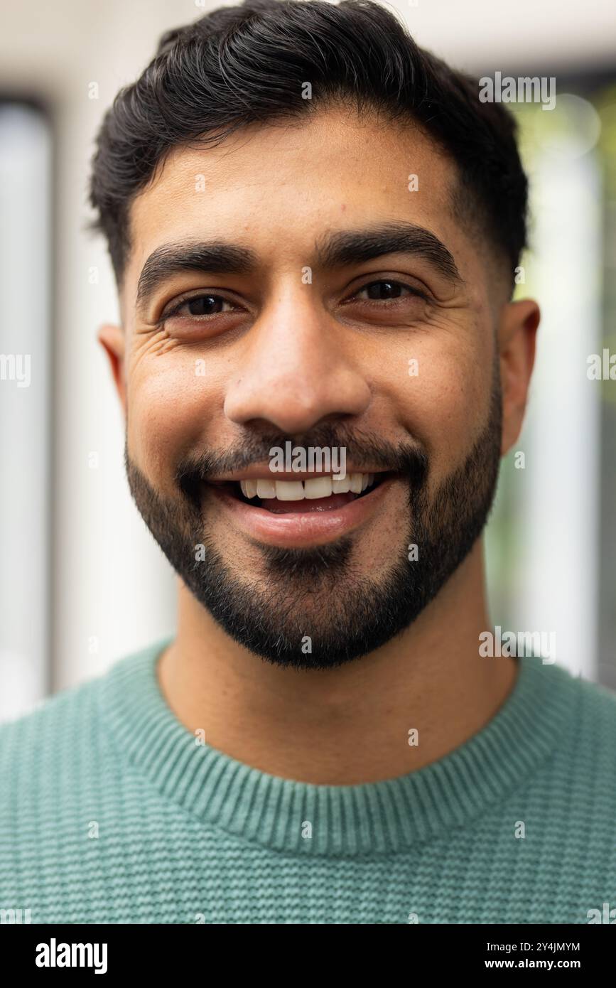Lächelnder junger Indianer in lässigem Pullover, der in die Kamera schaut, Nahporträt Stockfoto