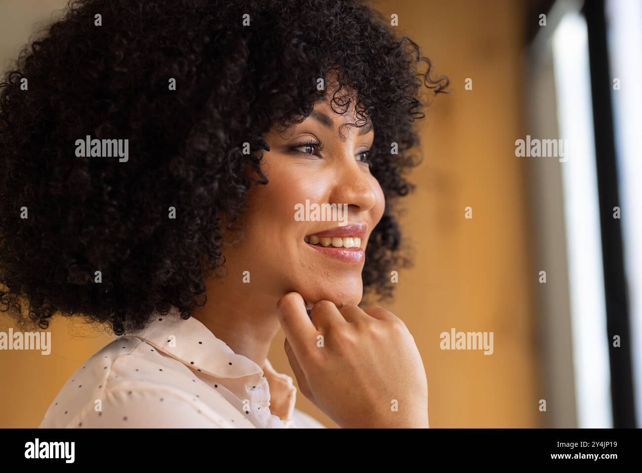 Aus dem Fenster blickend, lächelnde Geschäftsfrau, die über zukünftige Chancen nachdenkt Stockfoto