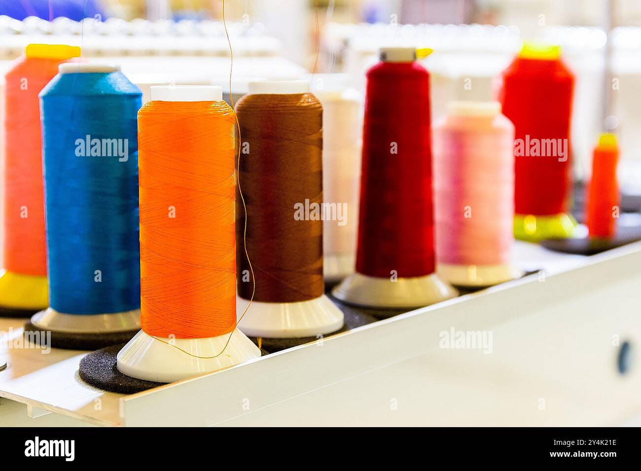 Spulen aus farbigem Faden auf einer industriellen Nähmaschine. Bekleidungsindustrie Stockfoto