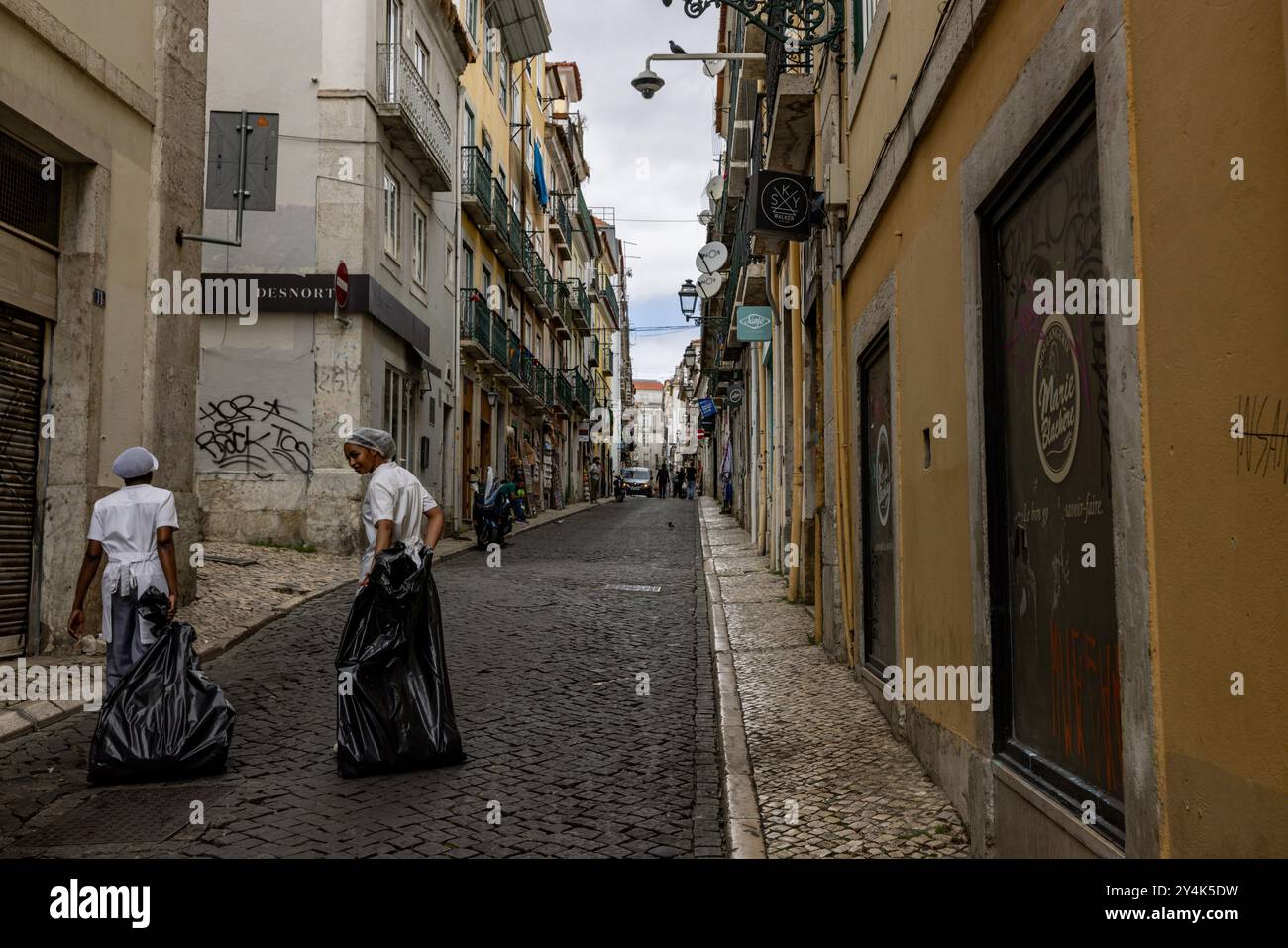 Zwei Arbeiter bringen Müll von ihrem Job in Lissabon, Portugal, auf die Straße Stockfoto