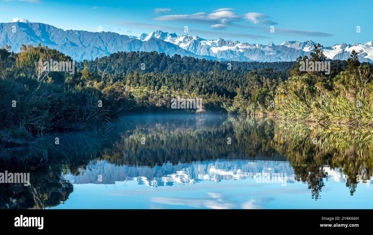 Der Regenwald der Westküste mit den südlichen Alpen im Hintergrund (aufgenommen in der Lagune von Okarito) Stockfoto