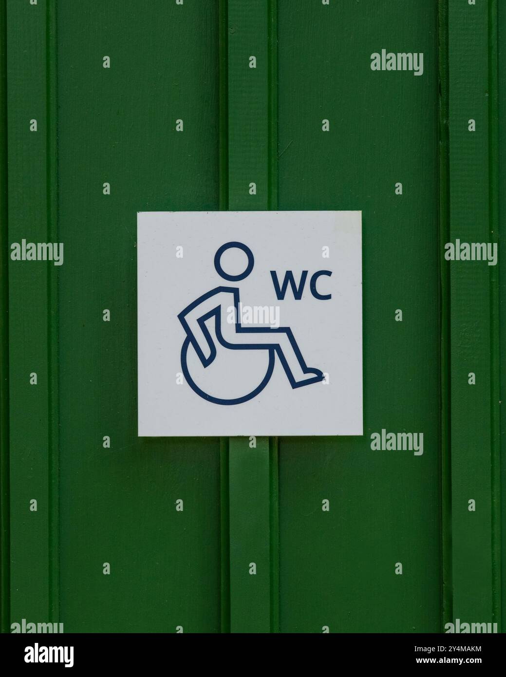 Rollstuhlschild und WC-Schild an grüner Tür. Kennzeichnung der Toilette für Menschen mit Behinderungen. Stockfoto