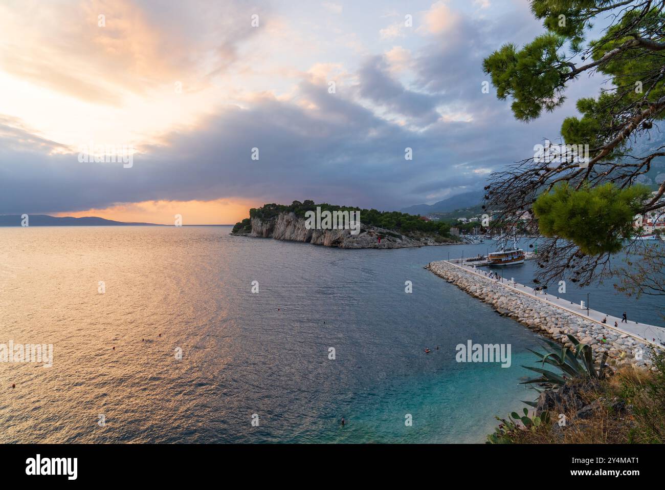 Wunderschöner Sonnenuntergang auf dem Meer. Touristenschiff aus Holz vertäut. Orangefarbene Wolken am Sonnenunterganghimmel. Kroatische Küste. Makarska. Sommerurlaub. Stockfoto