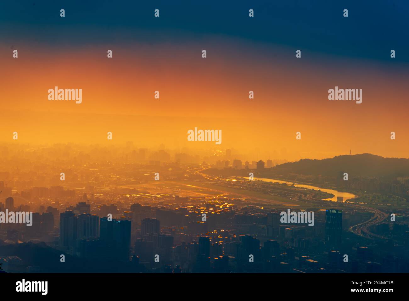 Ein Panoramablick auf Taipei City nach dem Regen, mit dem Keelung River durch die urbane Landschaft. Die untergehende Sonne strahlt ein warmes Leuchten über dem Stockfoto