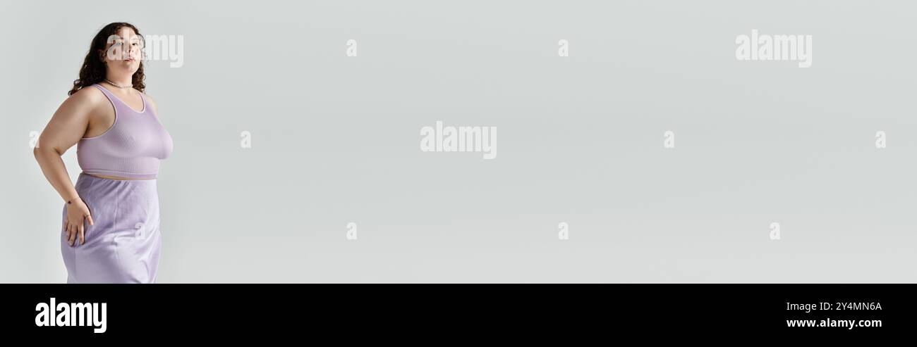 Eine strahlende Frau in Übergröße zeigt Selbstvertrauen und Eleganz in einem fließenden Lavendelkleid. Stockfoto