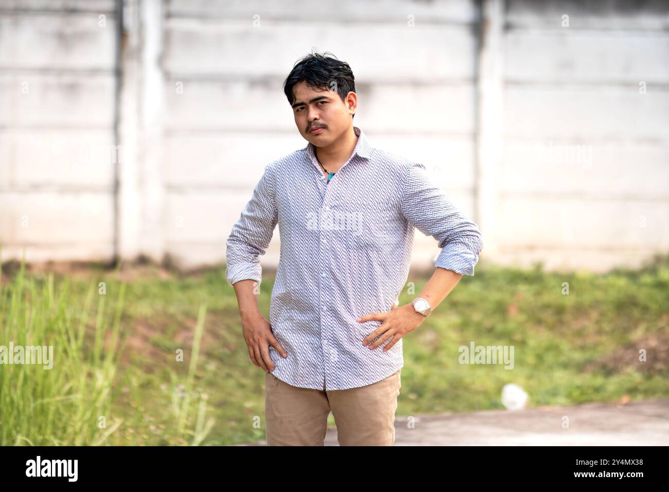 Porträt eines jungen Mannes mit ernstem und unglücklichem Gesichtsausblick in die Kamera. Männer mit wütendem Gesicht und Händen auf Hüften. Stockfoto