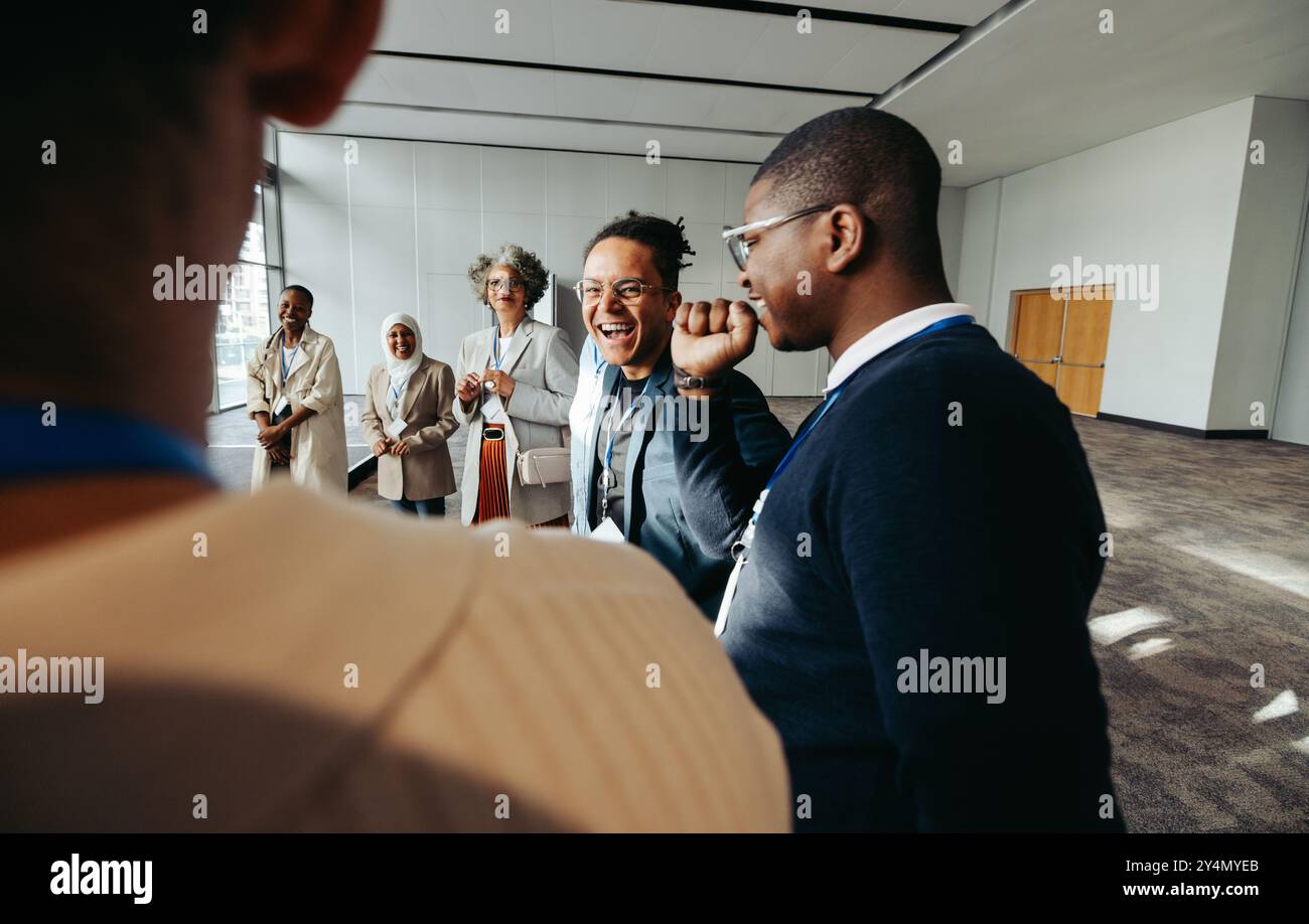 Eine Gruppe von fröhlichen Geschäftsleuten, die während eines Meetings in einem modernen Bürobereich lachen und sich engagieren. Die Atmosphäre ist freundlich und kooperativ. Stockfoto