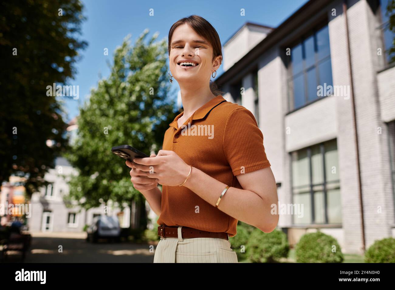 Eine freudige, nicht binäre Person greift in einem Büro im Freien an ihr Telefon. Stockfoto