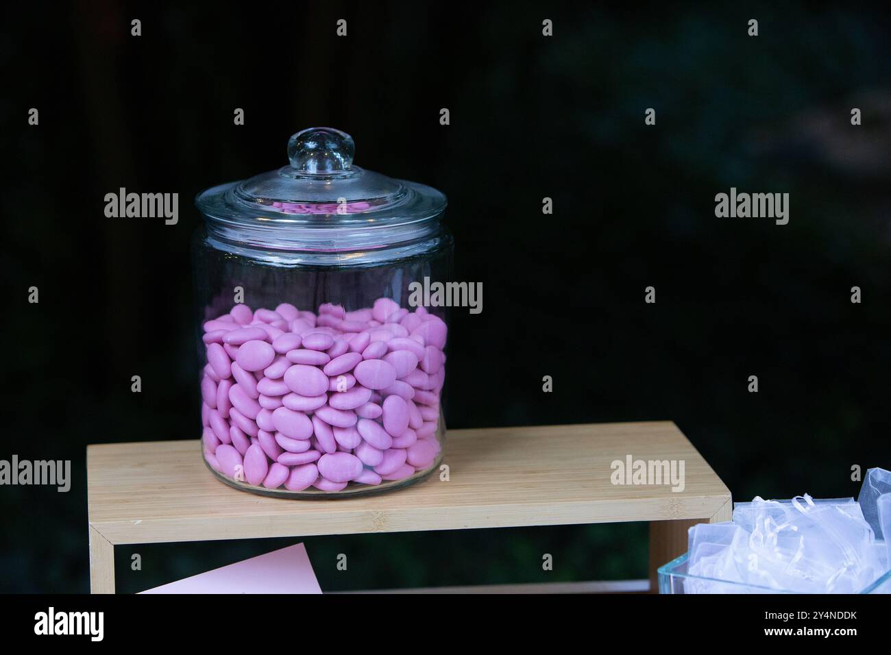 Ein Glasgefäß mit rosa Süßigkeiten steht auf einem Holzregal Stockfoto