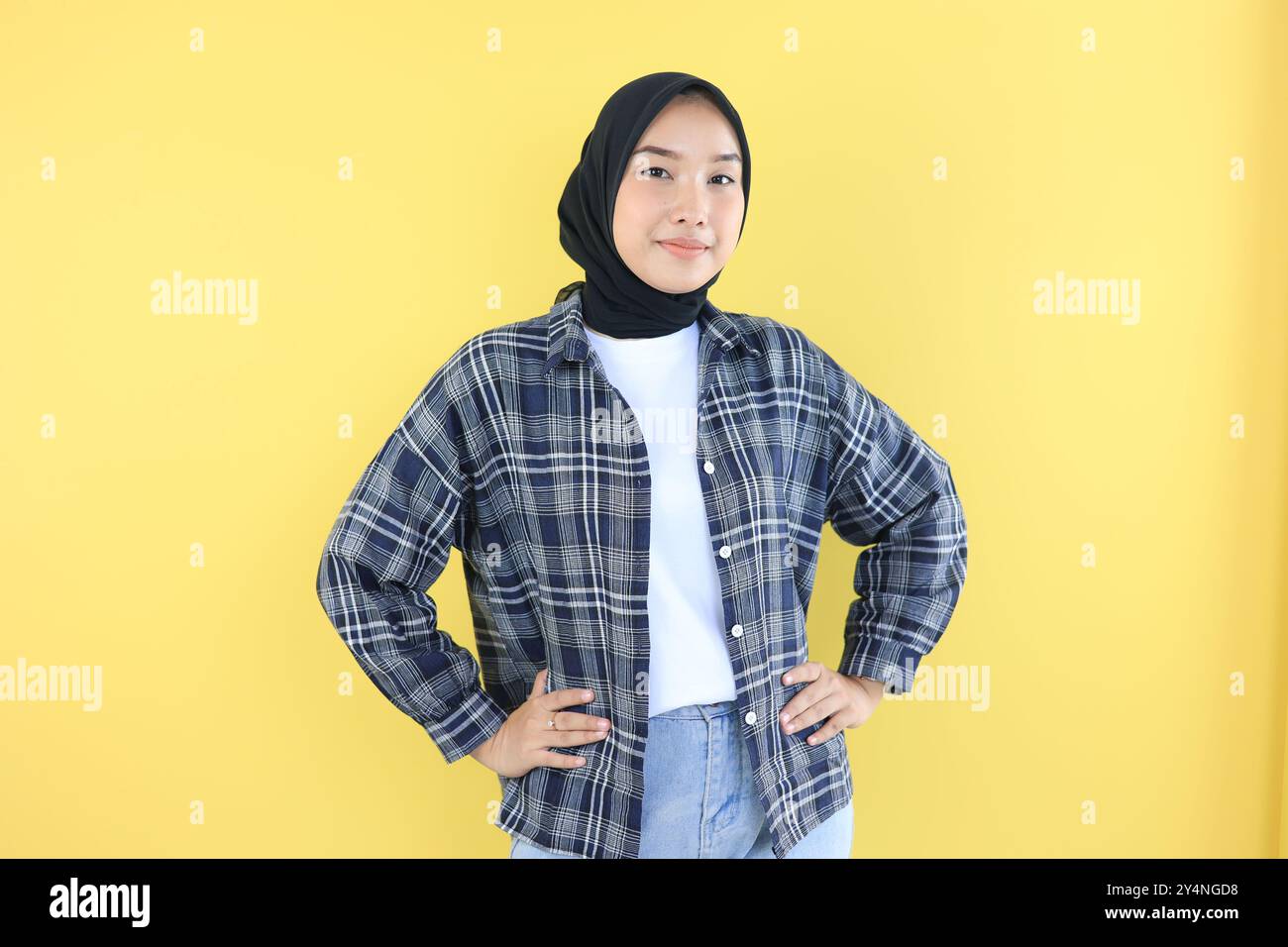 Asiatische junge Frau in Casual Fashion und Hijab, die sich selbstbewusst fühlt und mit Hand auf Hüften steht Stockfoto