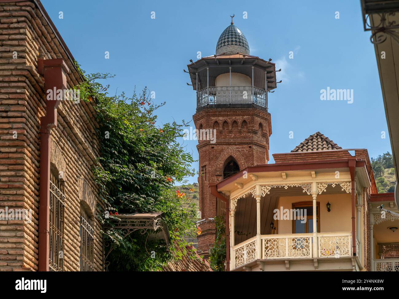 Minarett der Tiflis Moschee oder Juma Moschee und traditioneller georgianischer Holzbalkon unter der Festung Narikala Stockfoto