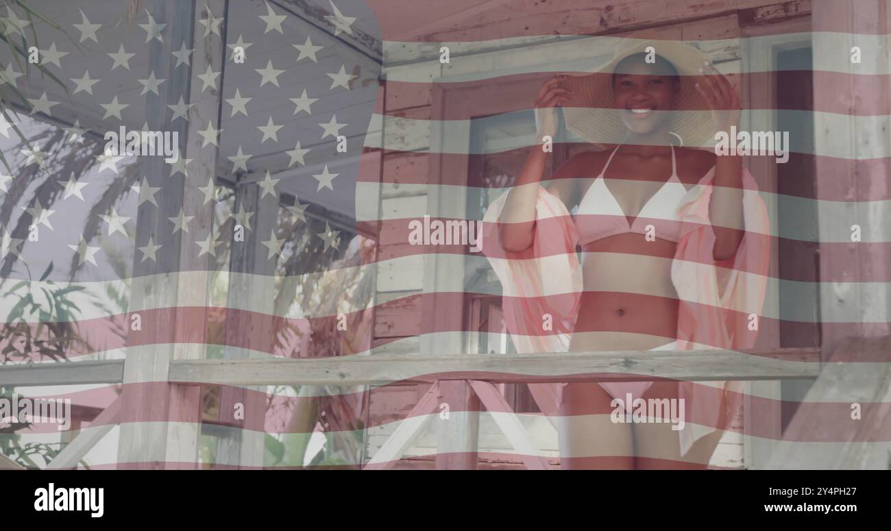 Bild der amerikanischen Flagge über der glücklichen afroamerikanerin, die Hut und Bikini in der Sonne trägt Stockfoto