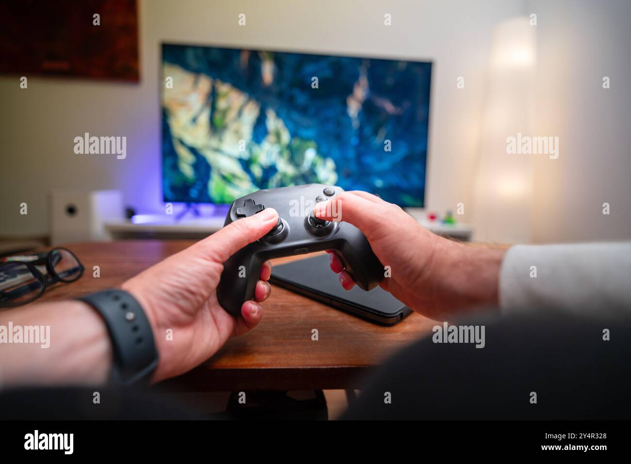 Spielkonsole Home Entertainment Gamepad mit Blick auf die Frontperson. Inneneinrichtung des Wohnzimmers mit TV-Bildschirm. Stockfoto