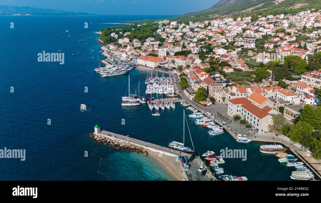 Der Hafen von Brac Island liegt an der malerischen Küste und bietet farbenfrohe Boote und bezaubernde Gebäude, Bol Brac Island Kroatien Stockfoto