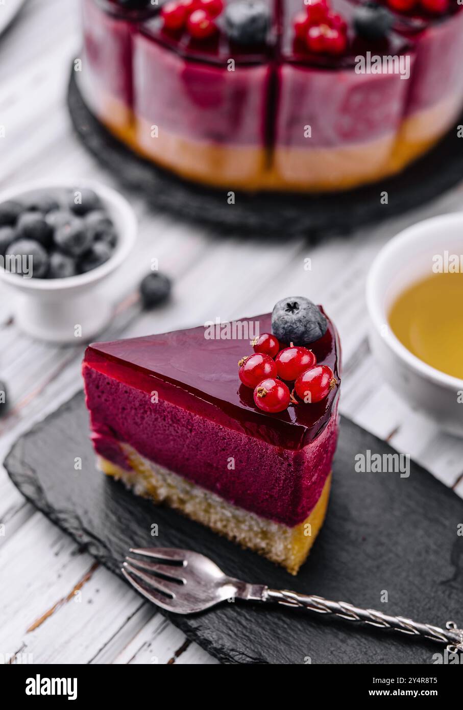 beeren-Mousse-Kuchen mit roter Glasur und Tee Stockfoto