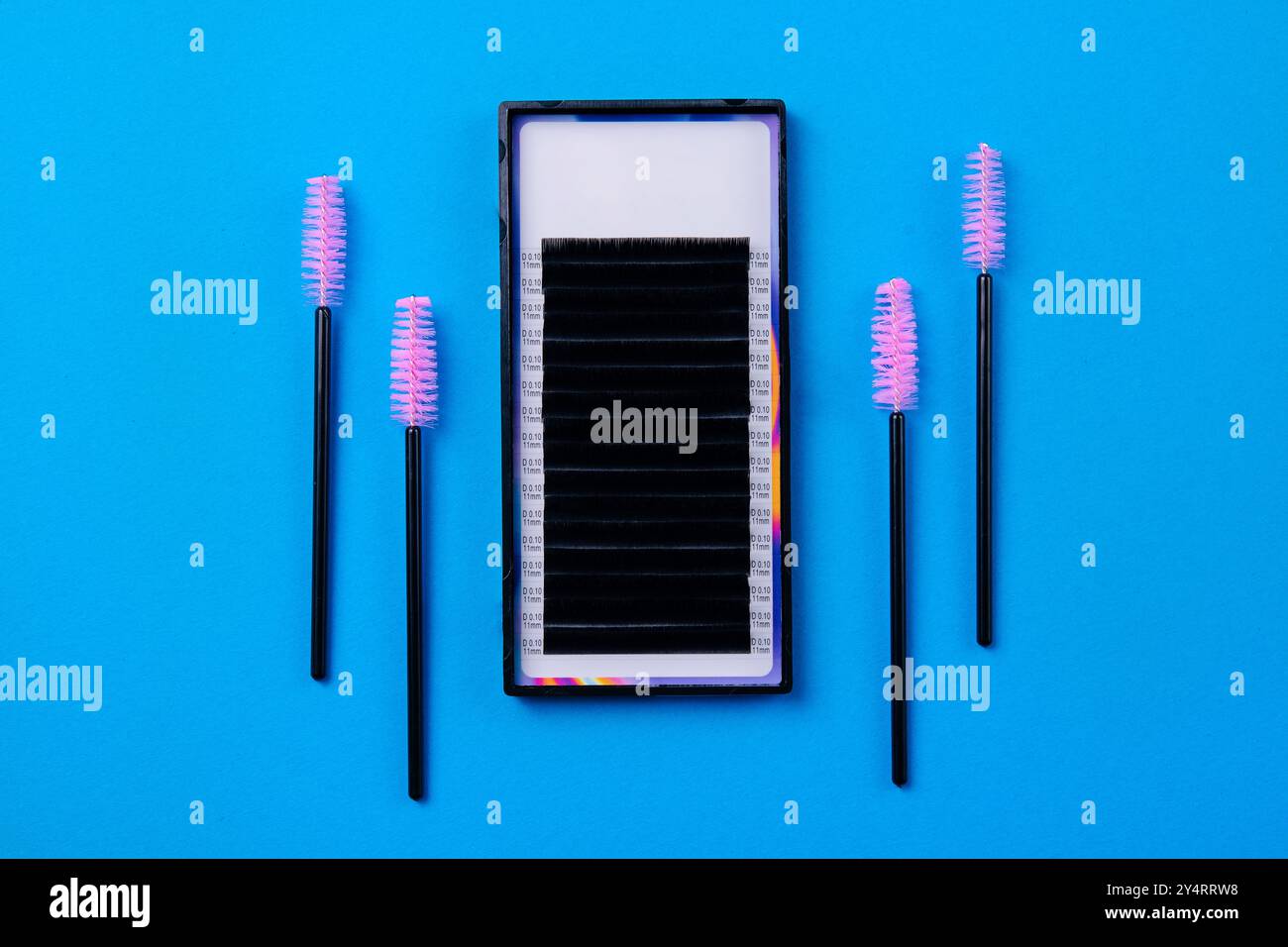Professionelle Wimpernverlängerung Zubehör und Werkzeuge ordentlich angeordnet auf einem leuchtend blauen Hintergrund Stockfoto
