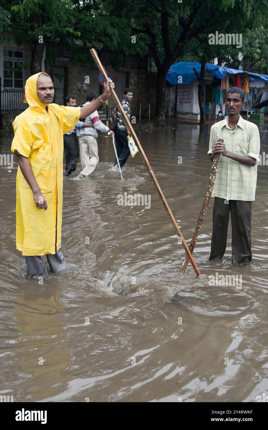 Mumbai, Maharashtra/Indien - 7. Juni 2008: Zwei Männer stehen am Entwässerungspunkt, um das Hochwasser von der Straße zu befreien. Stockfoto