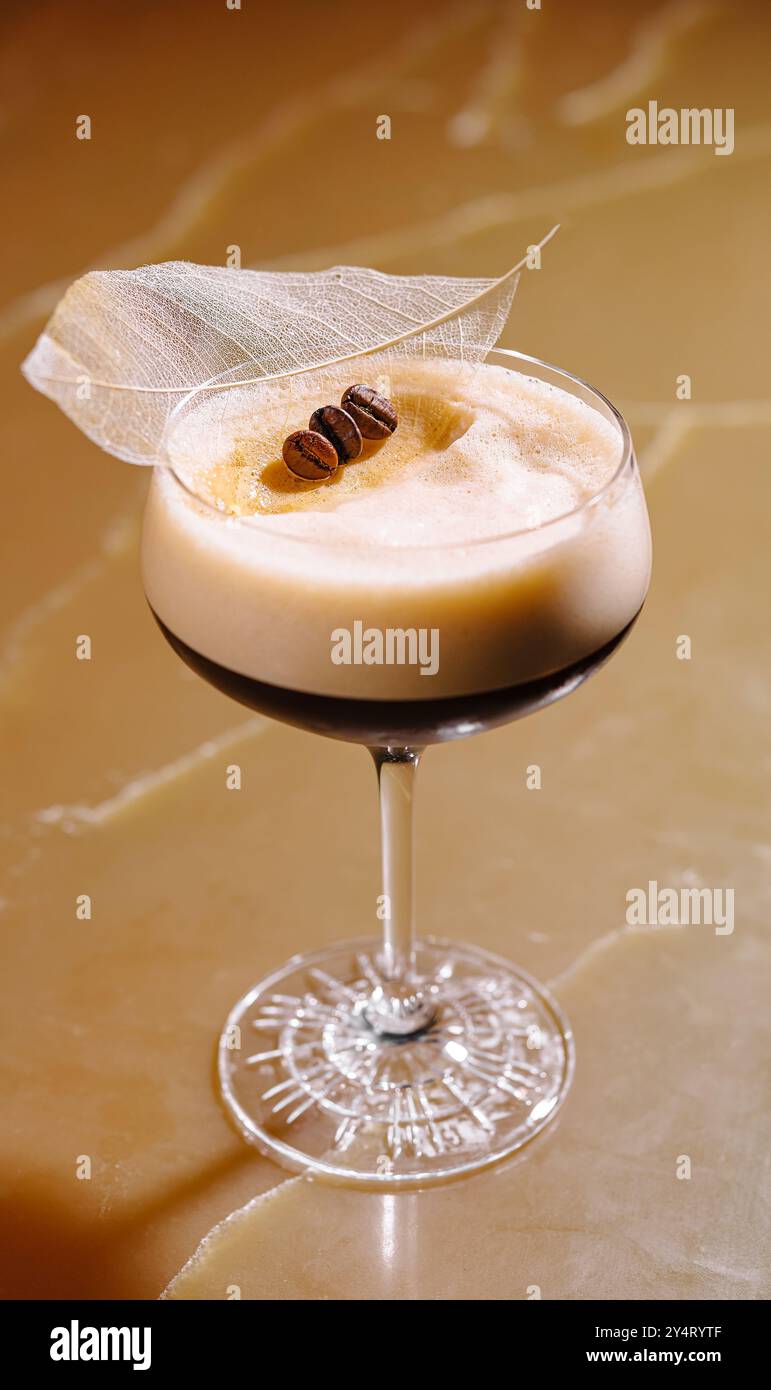 Raffinierter Espresso-Martini garniert mit Kaffeebohnen und einem zarten Blatt, serviert in einem klassischen Glas Stockfoto