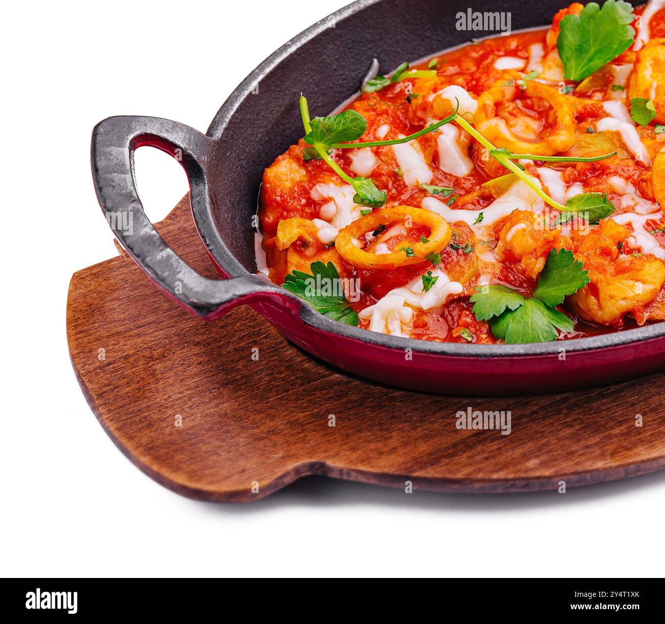 Appetitliche Meeresfrüchte-Mischung mit Kräutern in einer gusseisernen Pfanne auf einem Holzbrett isoliert auf weiß Stockfoto