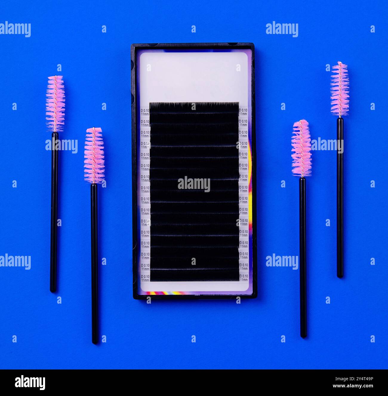 Professionelle Wimpernverlängerung Zubehör und Werkzeuge ordentlich angeordnet auf einem leuchtend blauen Hintergrund Stockfoto