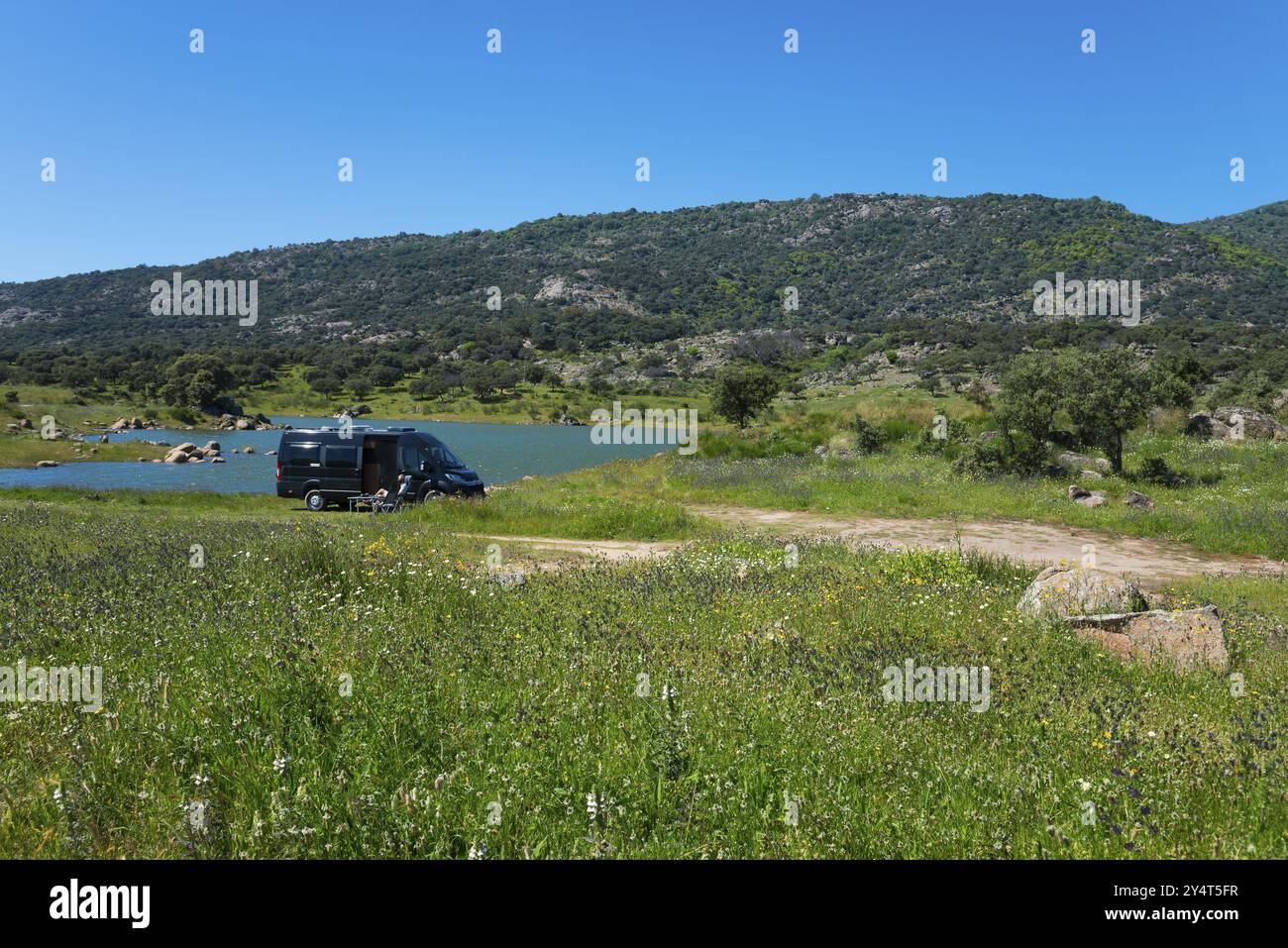 Wohnmobil auf einer grünen Wiese in der Nähe eines Sees, umgeben von Bergen und Bäumen an einem sonnigen Tag, Stausee Embalse de Plasencia, Embalse de Jerte, Ri¿½ Stockfoto
