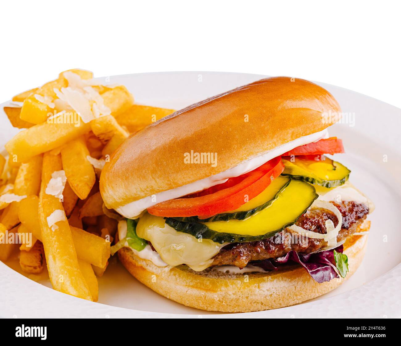 Saftiger Rindfleisch-Cheeseburger mit frischen Belägen und knusprigen Pommes frites, serviert auf einem weißen Teller Stockfoto